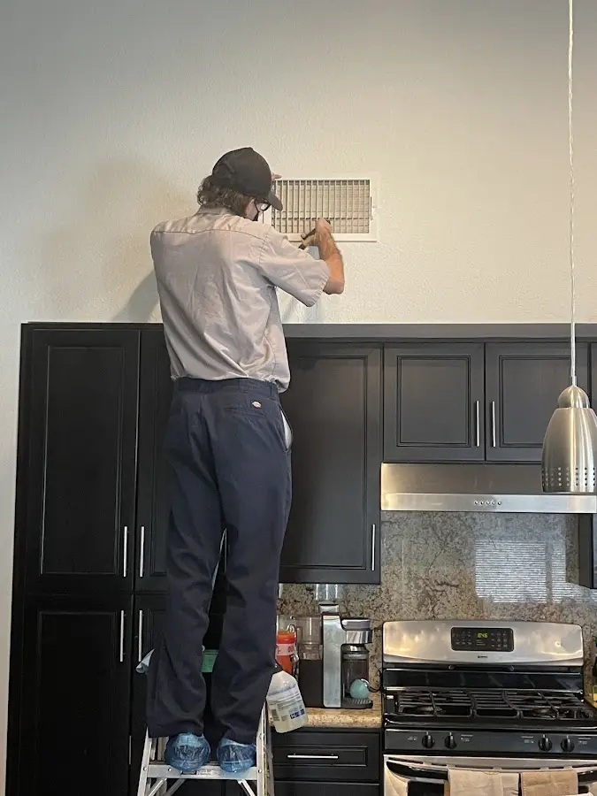 Technician inspecting an air vent during HVAC service in New Ulm